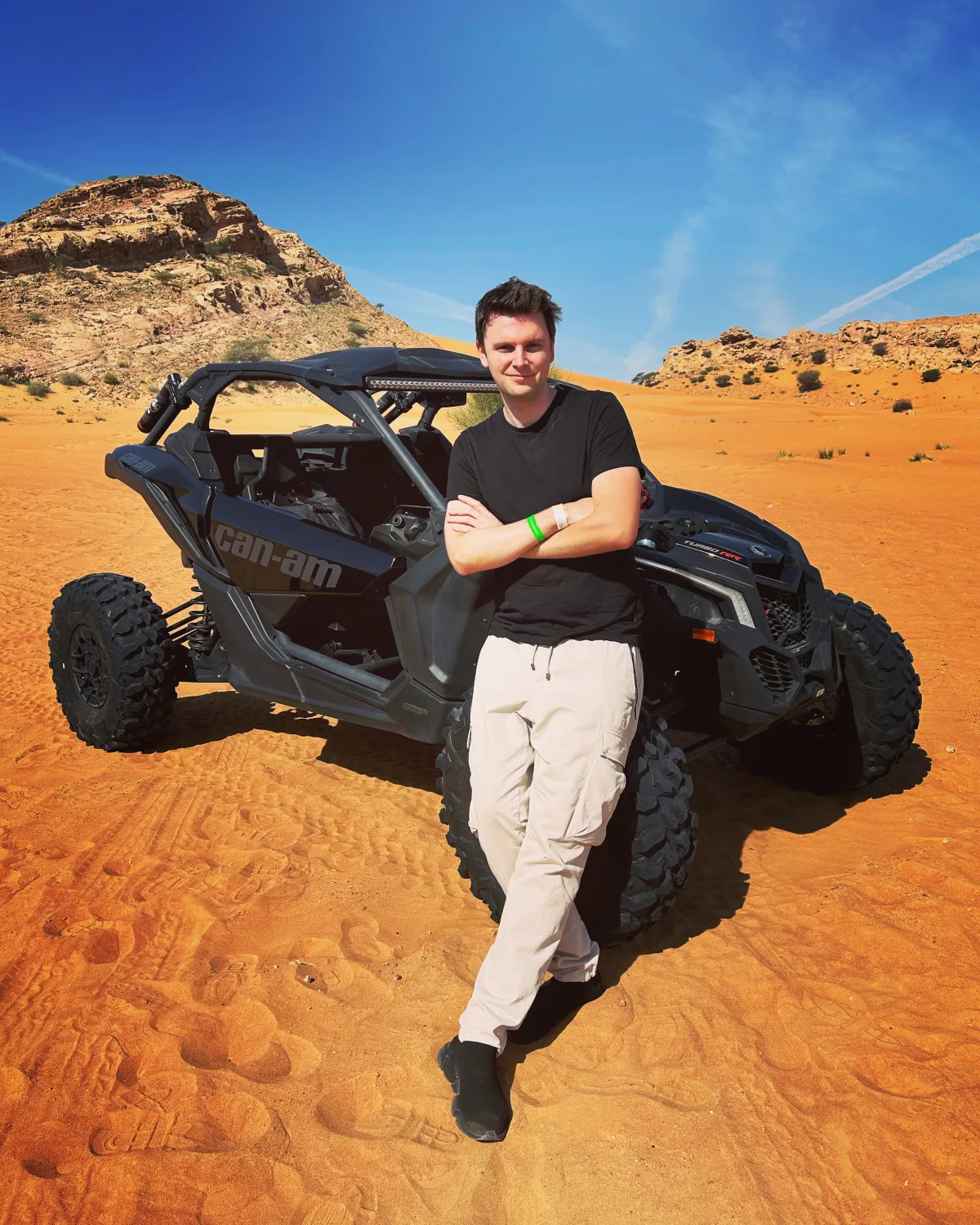 Frank Bendler lehnt an einem Buggy in der Wüste und schaut in die Kamera